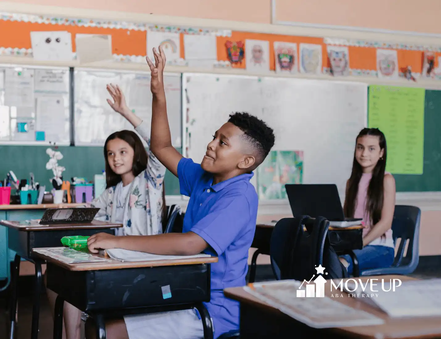 Autistic students sitting at desks in a classroom, raising hands to answer a question during school-based ABA therapy in MD.