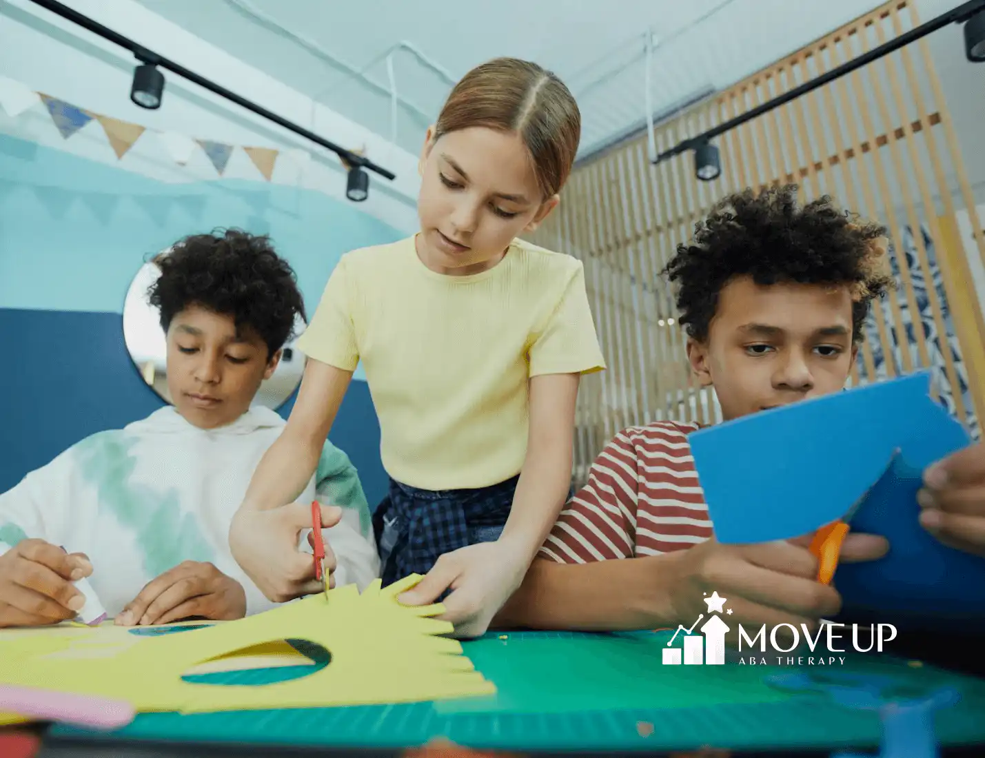 Three autistic kids focused on a paper craft activity at an art table during center-based ABA therapy in Maryland.