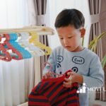 An autistic child hanging clothes on colorful hangers after in-home ABA therapy session.