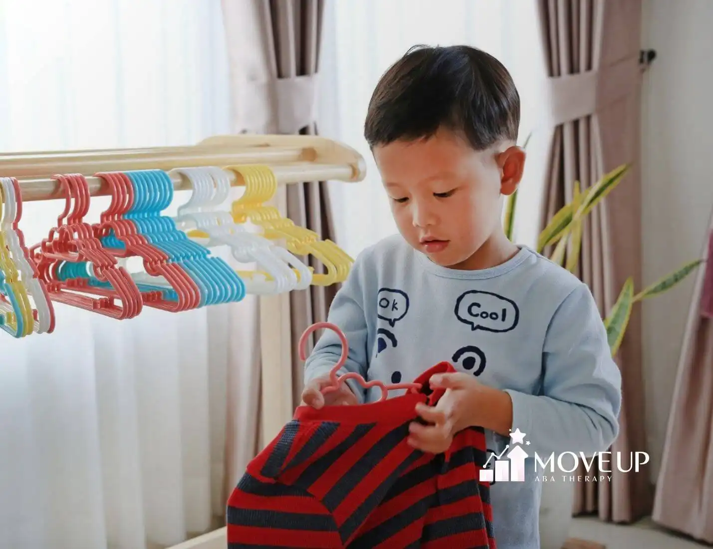 An autistic child hanging clothes on colorful hangers after in-home ABA therapy session.