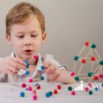 Autistic boy building a structure with sticks and colorful clay balls in ABA therapy.