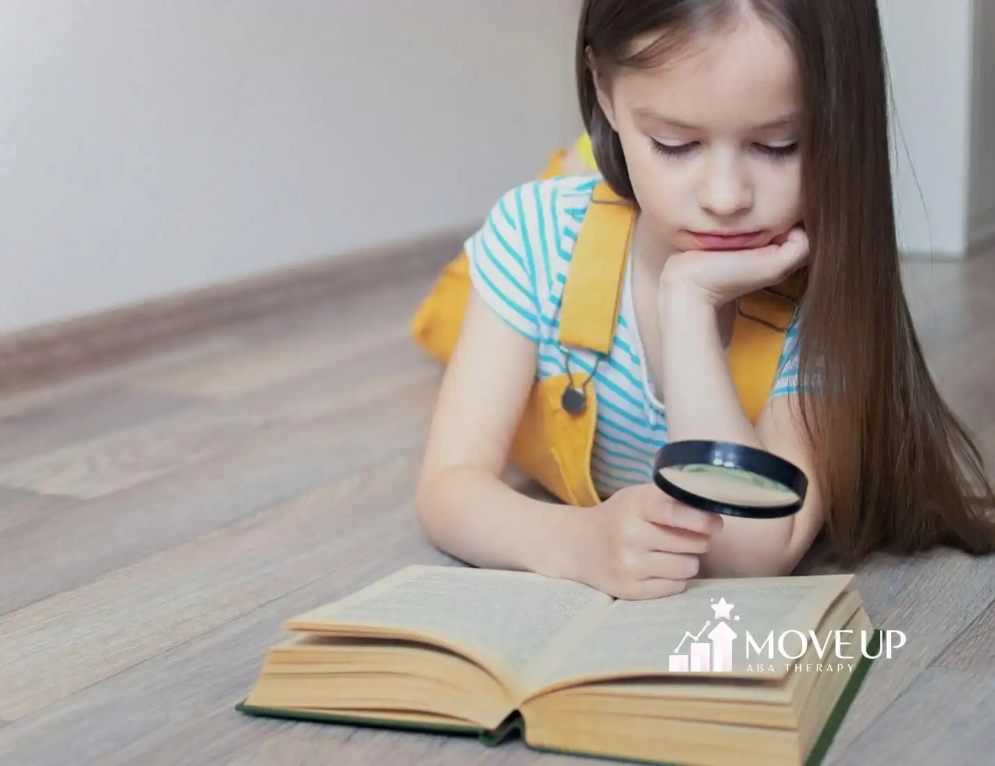 A girl with autism reading a book with a magnifying glass.