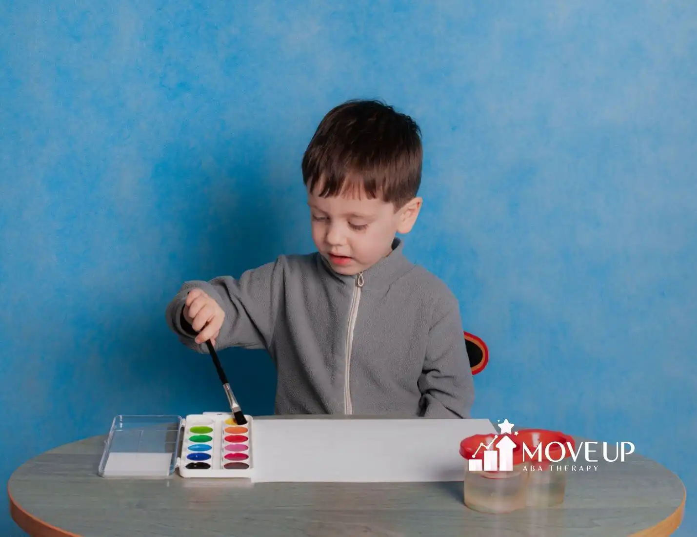 A child with autism painting with watercolors at a table.
