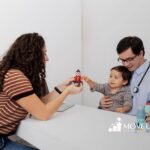 A toddler with autism playing with toy rockets during a doctor visit.