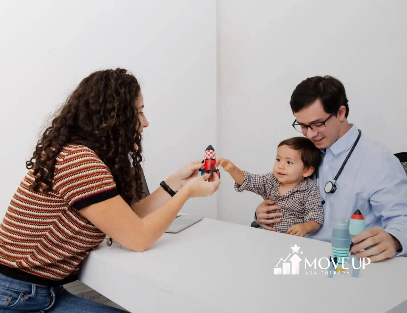 A toddler with autism playing with toy rockets during a doctor visit.