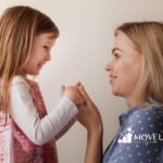 Smiling ABA therapist holding hands with an autistic girl in ABA therapy.