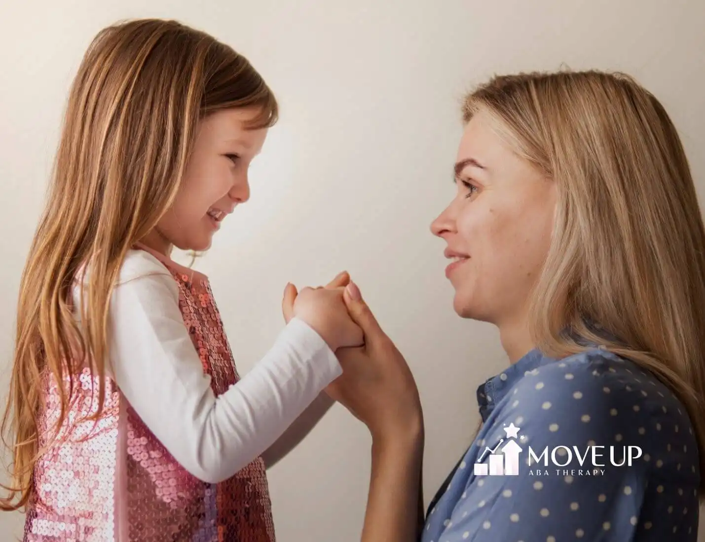 Smiling ABA therapist holding hands with an autistic girl in ABA therapy.