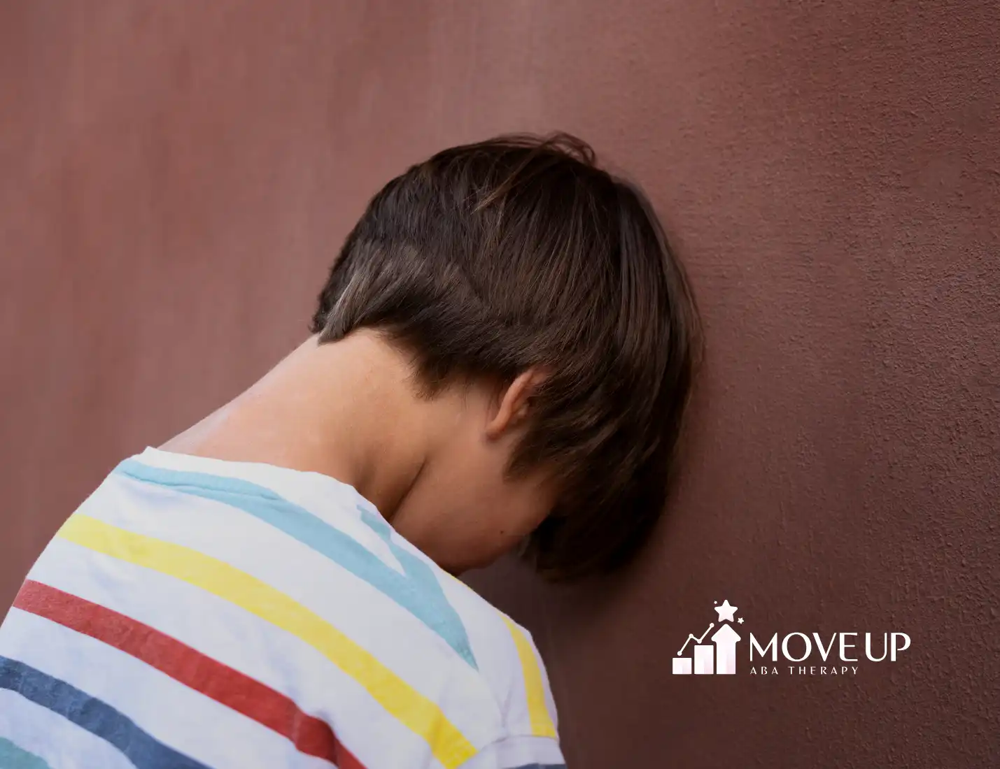 An autistic child with his head against the wall