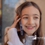 A child with autism is smiling while talking to someone over the phone