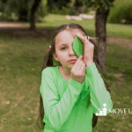A child with autism is covering her one eye with a leaf