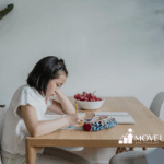 Young autistic girl is writing homework at wooden table during in-home ABA therapy session in Maryland.