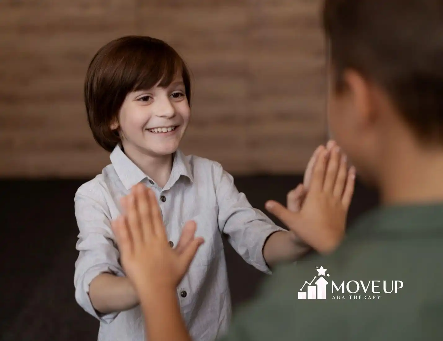 Two children with autism playing a hand game and smiling.