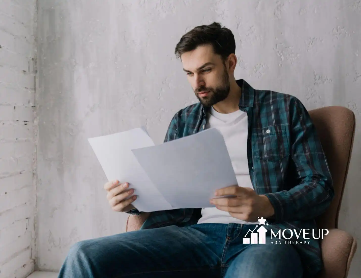A BCBA sitting in a chair, reading a behavior intervention plan with a thoughtful expression.