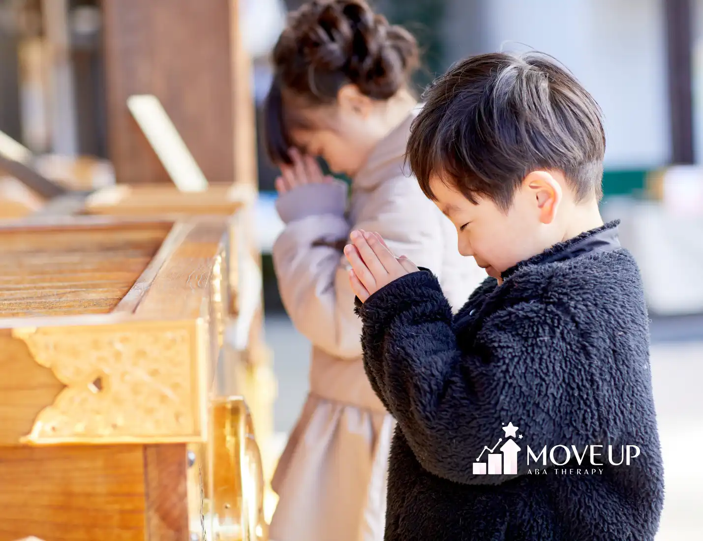 Two young children standing with hands pressed together in prayer at a place of worship