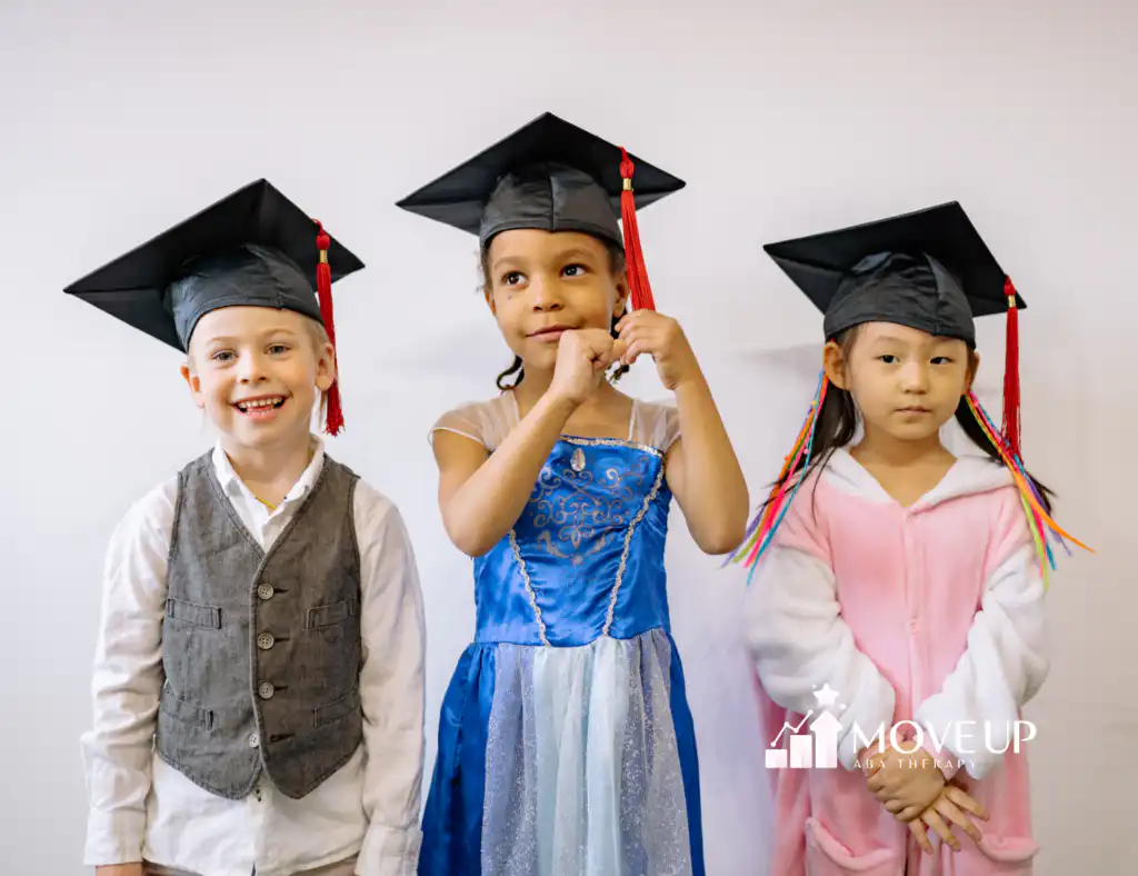 Three young children wearing graduation caps, dressed in a vest, a princess costume, and a bunny onesie, standing against a plain wall