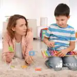 A mother lying on the floor, accompanying her son playing with the xylophone